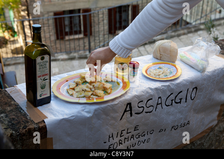 Touristen, die Verkostung des neuen Olivenöl mit Brot auf dem Holz Festival Wochenende alle Heiligen in Montone, Perugia, Umbrien, Italien. Temporären externen Shop einrichten für das Festival in den engen Gassen des mittelalterlichen Dorfes. 28/29/30-10 und 11.01.2011 Stockfoto