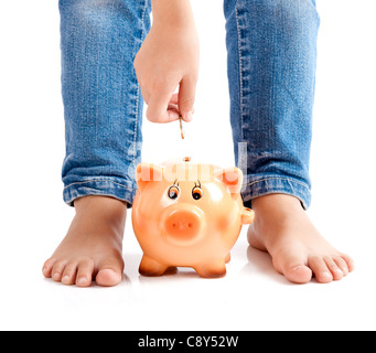 Einfügen einer Euro-Münze auf das Sparschwein Kind Stockfoto