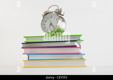 Stapel von bunte Bücher mit Wecker an der Spitze Stockfoto