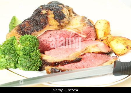 Eine geröstete Fuge von Balsamico glasiert Rindsfilet auf einem Teller mit Bratkartoffeln und gekochten Brokkoli und einem Schnitzmesser Stockfoto