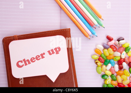 Rosa Notizbuch mit verschiedenen Farben von Bleistiften und Jelly Beans Stockfoto