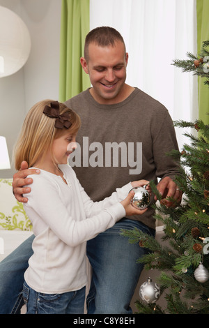 Vater und Tochter (6-7) dekorieren Weihnachtsbaum Stockfoto