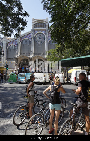 Gruppe junger Leute mit Fahrrädern vor zentralen Markthalle Mercado Central, Valencia, Spanien Stockfoto