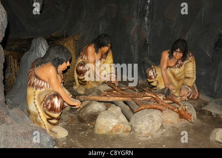 Neandertaler Menschen sitzen am Feuer in einer Höhle, Leba Park (prähistorische Freizeitpark), Polen Stockfoto