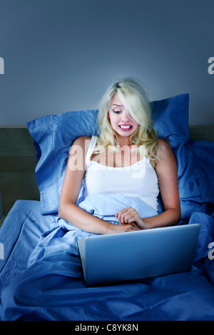 Angst vor Frau mit Laptop-Computer im Bett in der Nacht Stockfoto