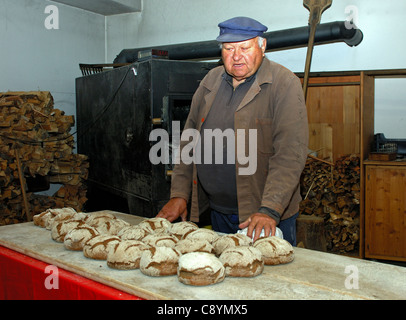 Bäcker mit frisch gebackenem Walliser Roggen Brot in der Dorfbäckerei Erschmatt, Wallis, Schweiz