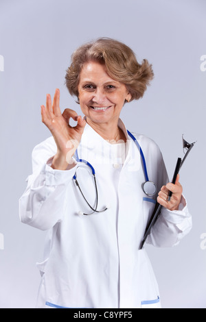 Glücklich Oberärztin gestikulieren "OK" zu Ihnen (isoliert auf grau) Stockfoto