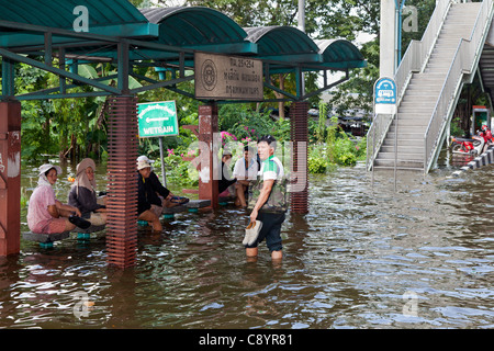 Menschen warten an einer Bushaltestelle, umgeben von Hochwasser im Stadtzentrum von Bangkok, Thailand Stockfoto