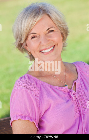Glückliche senior Frau draußen zu sitzen und Lächeln Stockfoto
