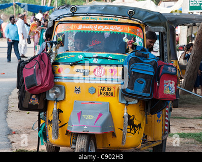 Indische Auto-rikscha voller Schulkinder mit ihren Taschen hängen an den Flügel. Andhra Pradesh, Indien Stockfoto