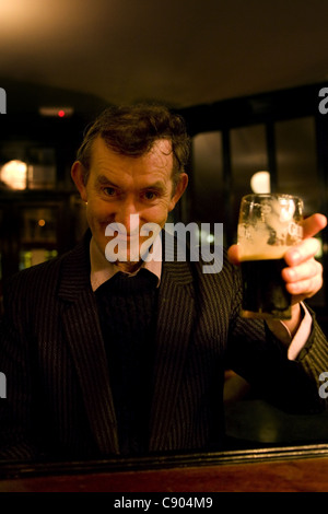 Alter Mann hält Glas Guinness Bier und lächelnd. Stockfoto