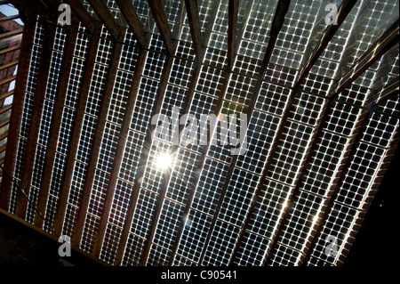 Die Sonne bricht durch das Innere der Solar Panals installiert auf dem Dach eines Gebäudes in der Mitte für Alternative Technologie, oder CAT, Europas führende Öko-Zentrum in Powys, Wales. Stockfoto