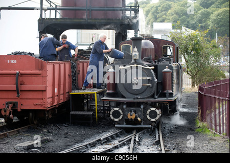 Der Lokführer von 2 Fuß Schmalspur Dampf Lok double Fairlie "Merddin Emrys" Kohlen seinen Motor aus einem Kohle-Wagen an Porthmadog Station auf die wieder-Bahn verläuft zwischen Porthmadog und Blaenau Ffestiniog, Snowdonia, North Wales, UK. Stockfoto