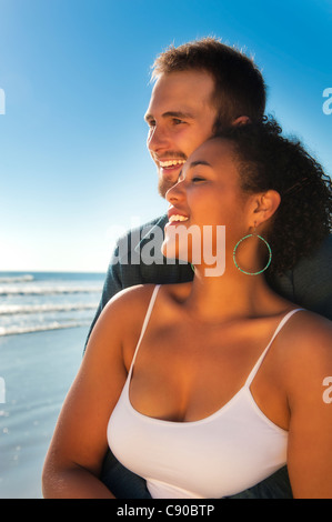Junges Paar 20er Jahre am Strand blauen Himmel Ozean in Liebe Lächeln, lachen, genießen Freizeitkleidung weißen Leibchen Stockfoto