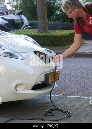 Mann, Einstecken in seinem Nissan Leaf Elektroauto, Amsterdam, Niederlande Stockfoto