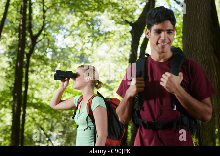 junge Menschen unter Bäumen wandern und Vögel mit dem Fernglas zu betrachten. Horizontale Form, Seitenansicht, Hüfte aufwärts Stockfoto