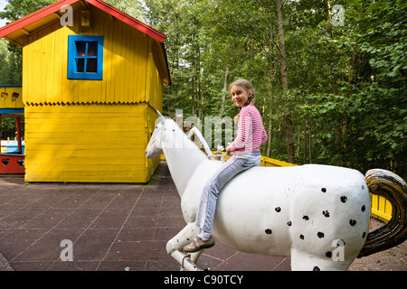 Mädchen sitzen auf einem hölzernen Pferd, Astrid Lindgren Vaerld, Astrid Lindgren World, Vimmerby, Småland, Südschweden, Europa Stockfoto