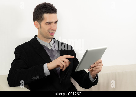 Geschäftsmann auf Sofa sitzen und einen digitale Tablet-pc verwenden. Stockfoto
