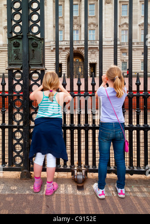 Zwei junge Mädchen Touristen fotografieren vor den Toren des Buckingham Palace Westminster London England UK Stockfoto