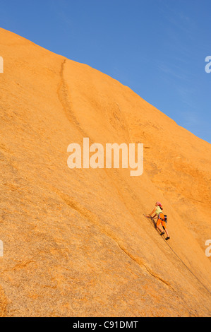 Frau Klettern am roten Felswand, große Spitzkoppe, Namibia Stockfoto