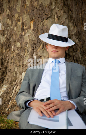 Geschäftsmann Nickerchen auf Baum im park Stockfoto