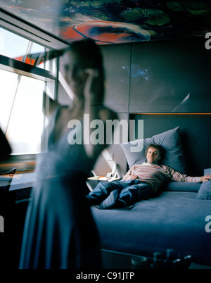 Reflexion von einer Frau bekommen gekleidet Mann liegt auf dem Bett Suite auf der 13. Etage-Designed by Jean Nouvel Hotel Silken beobachten Stockfoto