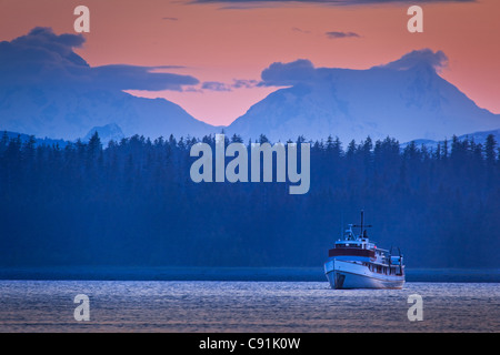 Ein Boot Segeln in Bartlett Cove bei Sonnenuntergang mit Fairweather Range im Hintergrund, Glacier Bay Nationalpark & Preserve, Alaska Stockfoto