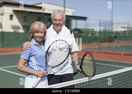 Älteres Ehepaar umarmt auf Tennisplatz Stockfoto