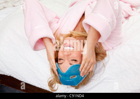 Frau auf Bett mit Augenmaske auf Stirn Stockfoto