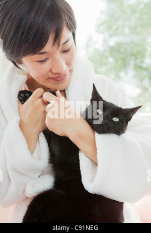 Frau im Bademantel Holding Katze Stockfoto