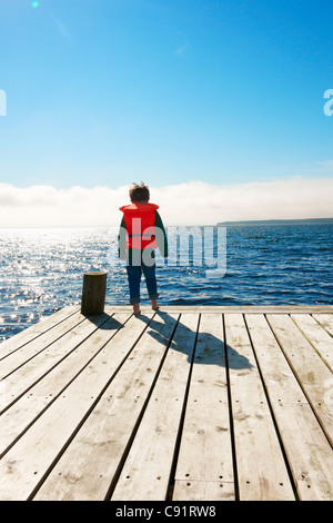 Jungen tragen Rettungsweste auf hölzerne pier Stockfoto