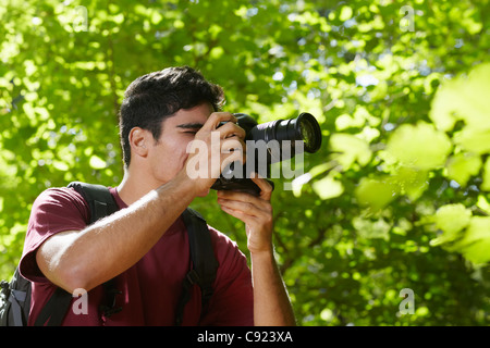 hispanische Jüngling trekking zwischen Bäumen und Fotografieren mit Dslr-Kamera. Horizontale Form, Seitenansicht, Textfreiraum Stockfoto