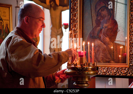 Mann zündet Kerzen vor der Ikone, Fürbitten des Heiligen während Russisch-Orthodoxe Weihnachten, Kodiak, Alaska zu suchen Stockfoto