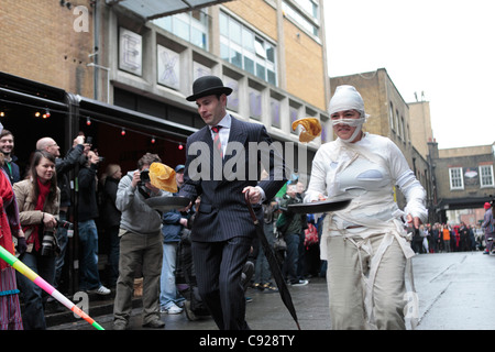 Schrullige jährliche Great Spitalfields Pancake Race gehalten am Faschingsdienstag, Fastnacht, an die Old Truman Brewery, London, England Stockfoto