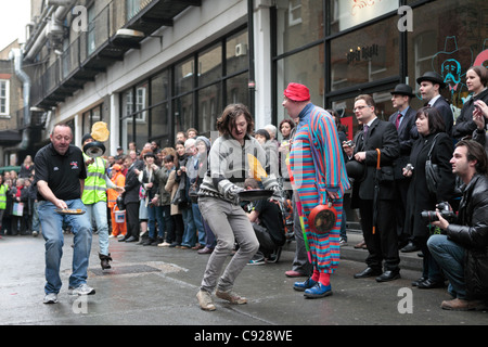 Schrullige jährliche Great Spitalfields Pancake Race gehalten am Faschingsdienstag, Fastnacht, an die Old Truman Brewery, London, England Stockfoto