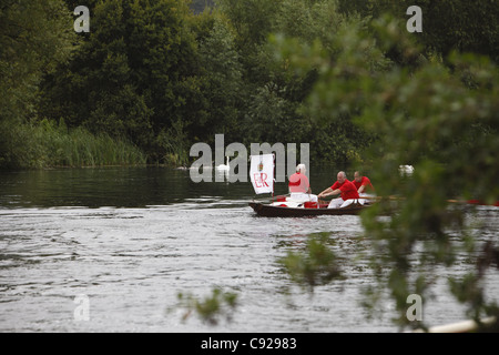 Swan-Oberteil in ihren traditionellen scarlet einheitliche Zeile Skiffs den Fluss hinunter, während Swan Upping, Themse, Henley, England Stockfoto