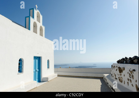 Ansicht der weiß getünchten Santorini griechisch-orthodoxe Kirche geschmückt mit blau umrandet Arkaden mit christlichen Kreuz gekrönt. Stockfoto