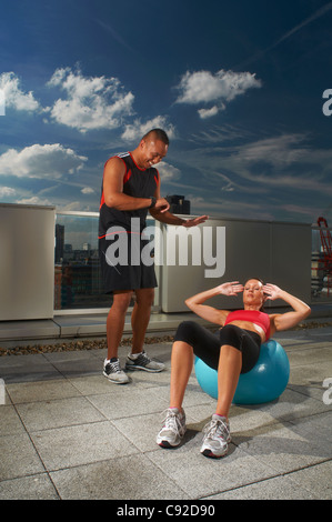 Frau, die das Training mit Trainer auf Dach Stockfoto
