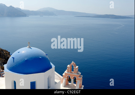 Blick auf die blaue Kuppel griechisch-orthodoxen Anastasis Kirche mit Blick auf das azurblaue Wasser des Santorini Caldera. Stockfoto