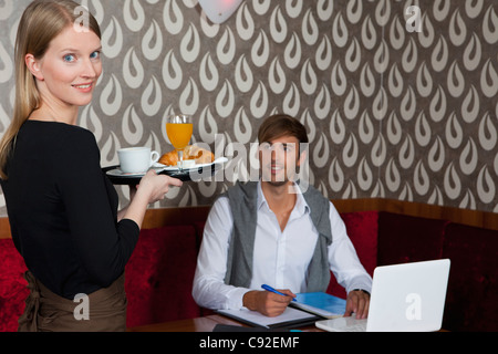 Kellnerin serviert Frühstück, Mann Stockfoto