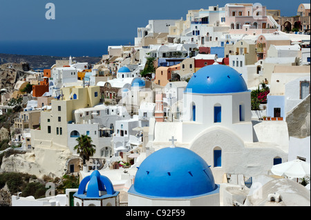 Blick auf die malerische Santorin Oia mit seinem Mix aus blauen Kuppelkirchen, weiß getünchten Häusern und Pastellfarben. Stockfoto