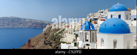 Panoramablick von der Caldera, blaues Meer und das Dorf Oia mit mit seinem Mix aus blauen Kuppelkirchen und weiß getünchten Häusern. Stockfoto