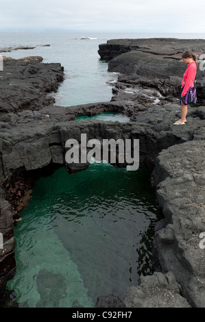 Frau steht auf einem Felsen, Ecuador, Galapagos-Inseln, Insel Santiago, Puerto Egas Stockfoto