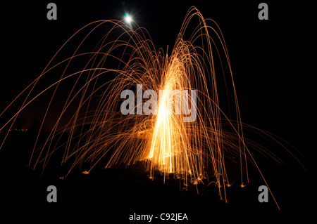 Stahl Wolle spinnen. Erfordert der Fotograf Feuer zu einem Büschel von Stahlwolle, versteckt in einem Draht Schneebesen zu einer langen, dicken Kabel angeschlossen, oder Seil Stockfoto