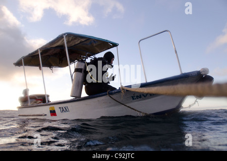 Scuba Diver sitzt auf der Kante eines Bootes, San Cristobal Insel, Galapagos-Inseln, Ecuador Stockfoto