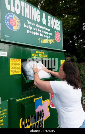 Eine Frau legt einen Beutel mit Kleidung in einer Heilsarmee-Charity-Sammelstelle für unerwünschte Kleidung & Schuhe. Stockfoto