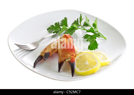 Crab Claws, Zitronenspalten und ein Bund Petersilie auf einer Platte anrichten. Stockfoto