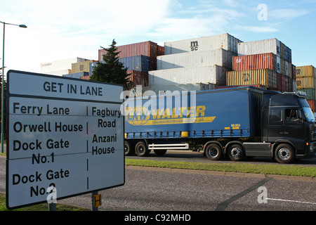 Container-Truck vorbei an gestapelten Containern und ein Schild zeigt Richtungen zu Port Felixtsowe Stockfoto