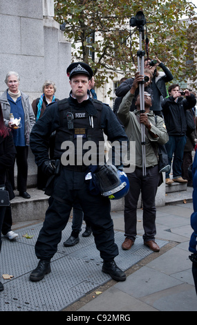 London, UK. 9. November 2011. Offizier steht fest, während Menschen im Hintergrund zu sehen. Stockfoto