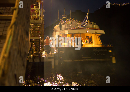 Santorini - ein Shuttleboot Touristen kehrt das Kreuzfahrtschiff MSC Armonia, nach Einbruch der Dunkelheit - wieder einschiffen. Stockfoto